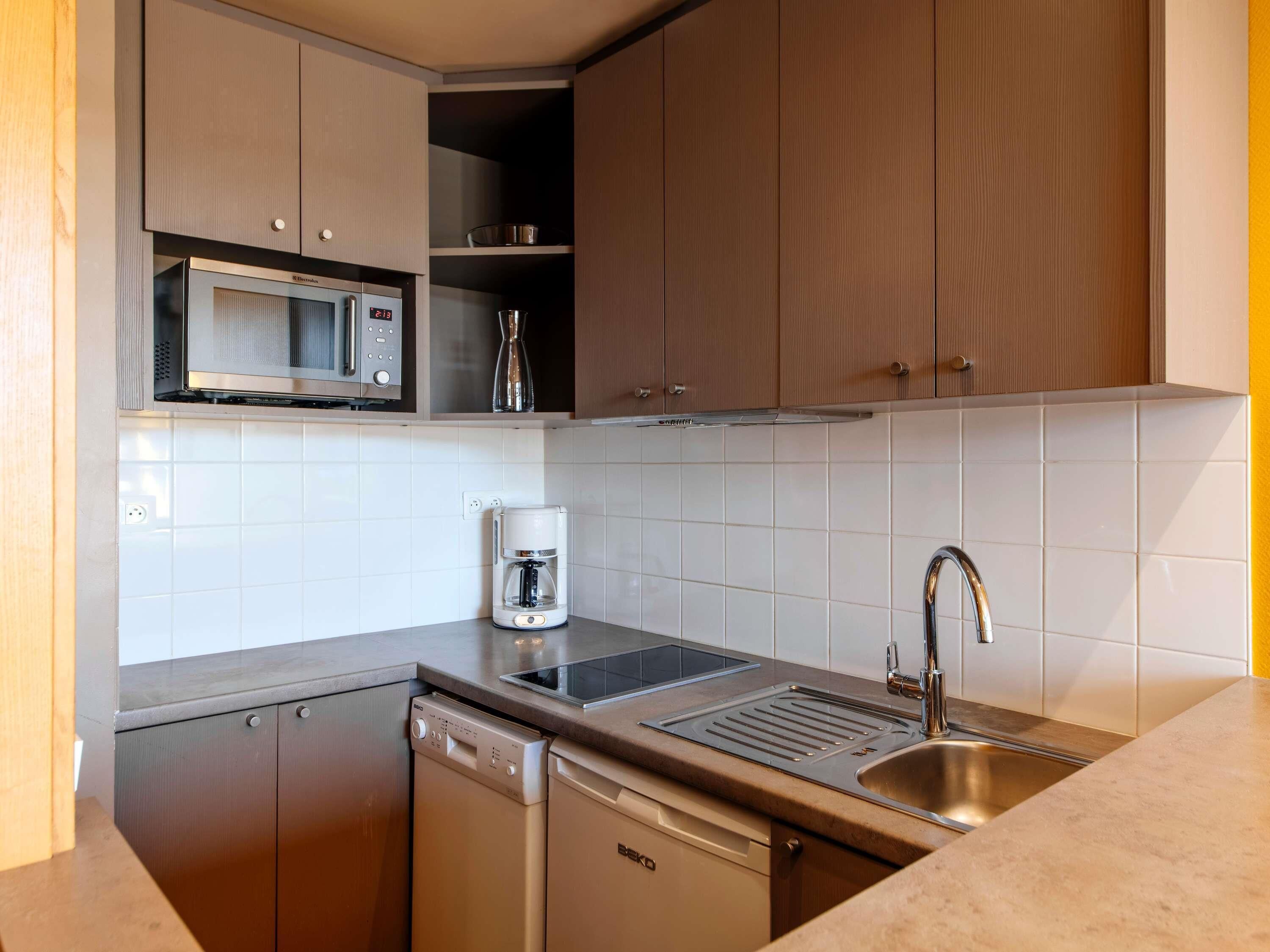 A compact kitchen with a microwave, coffee maker, sink, and dishwasher.