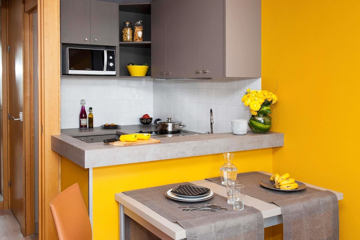 Una cocina compacta con microondas, lavamanos y un comedor con una mesa lista para dos.