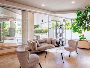 A modern interior with a sofa, two armchairs, a coffee table, and a large potted plant.