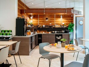 A modern cafe with a central island, seating area, and a visible kitchen in the background.