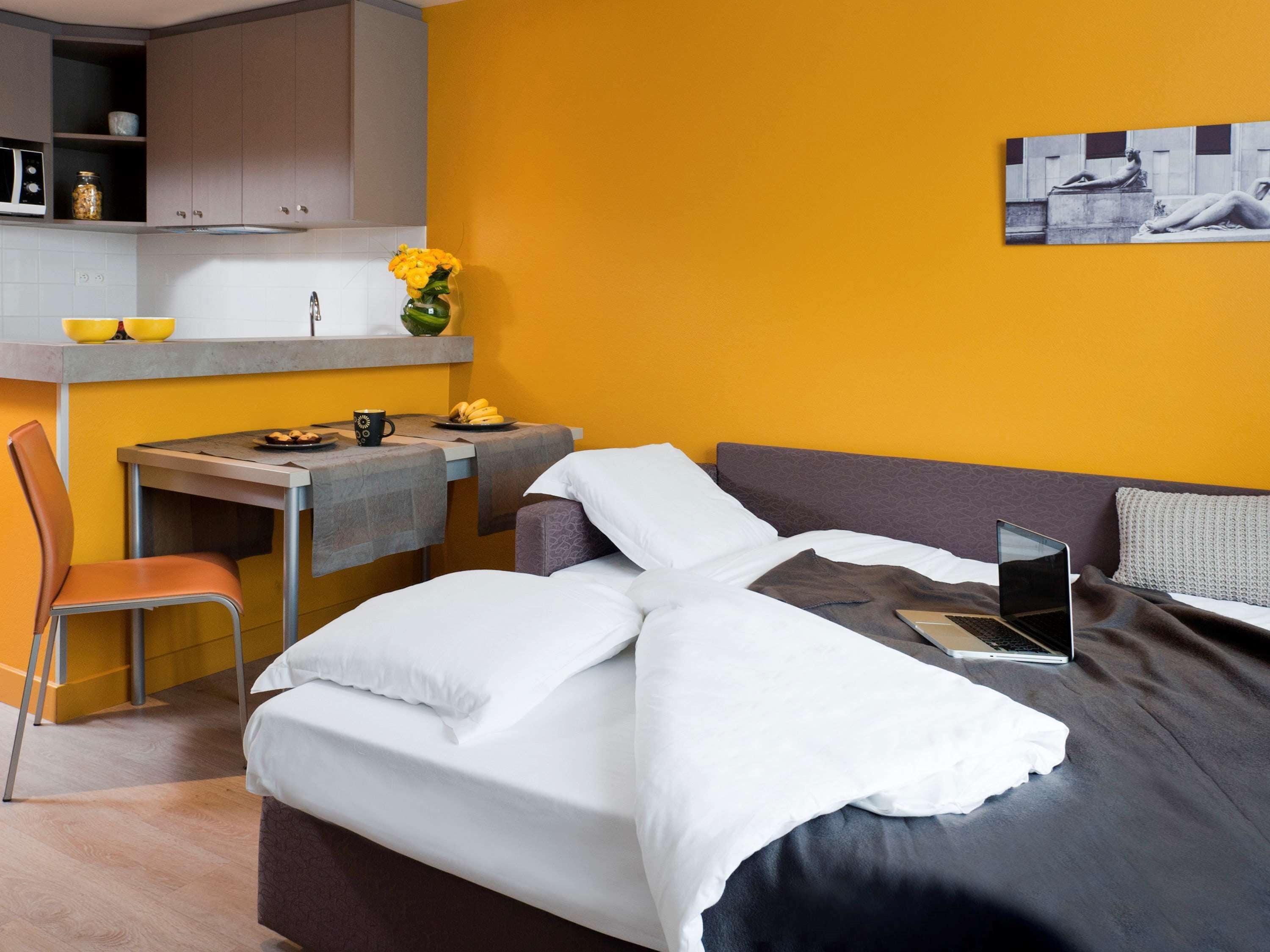 Una habitación de hotel pequeña con una cama, un escritorio y una silla.