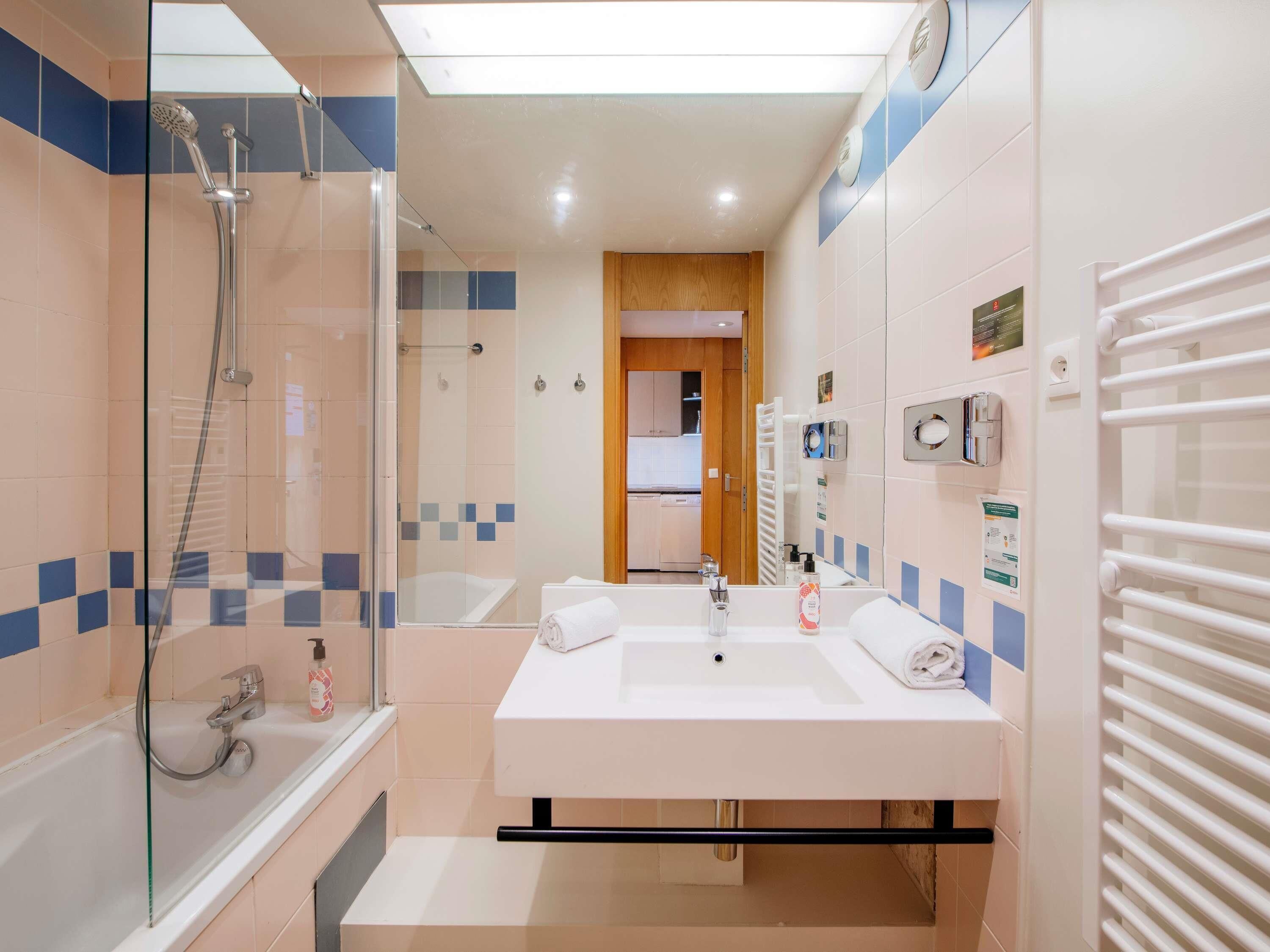Ein modernes Badezimmer mit einer Duschkabine, einer Badewanne, einem großen Waschbecken mit Spiegel und einem Handtuchhalter.