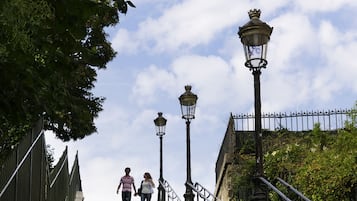 A set of stone steps with metal railings and street lamps, leading up to a building.