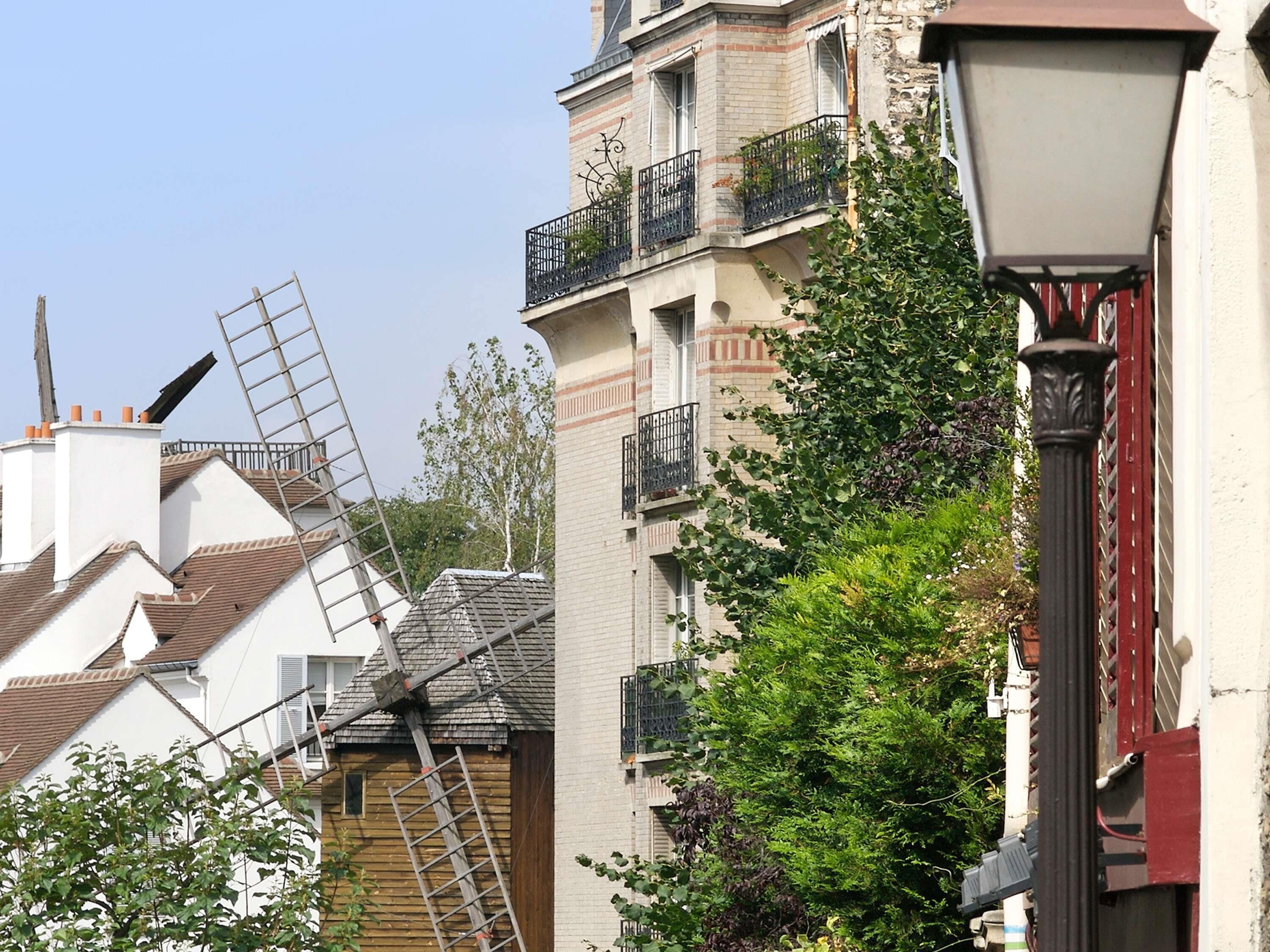 A building with a windmill, a street lamp, and a tree.