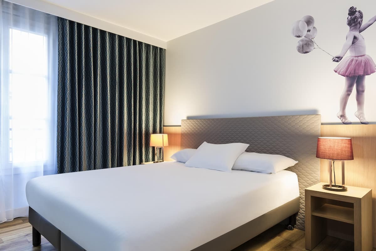 Een hotelkamer met een groot bed, twee nachtkastjes, een hoofdeinde en een aan de muur hangend schilderij.