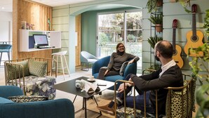 Um interior moderno com área de estar, um laptop numa mesa e uma guitarra na parede.