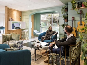 A modern interior with a seating area, a laptop on a desk, and a guitar wall. - Aparthotel Adagio Paris Montmartre (Paris)