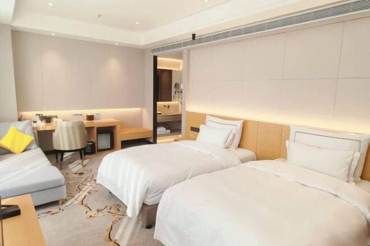 Una habitación de hotel con dos camas, un escritorio, una silla y un espejo.
