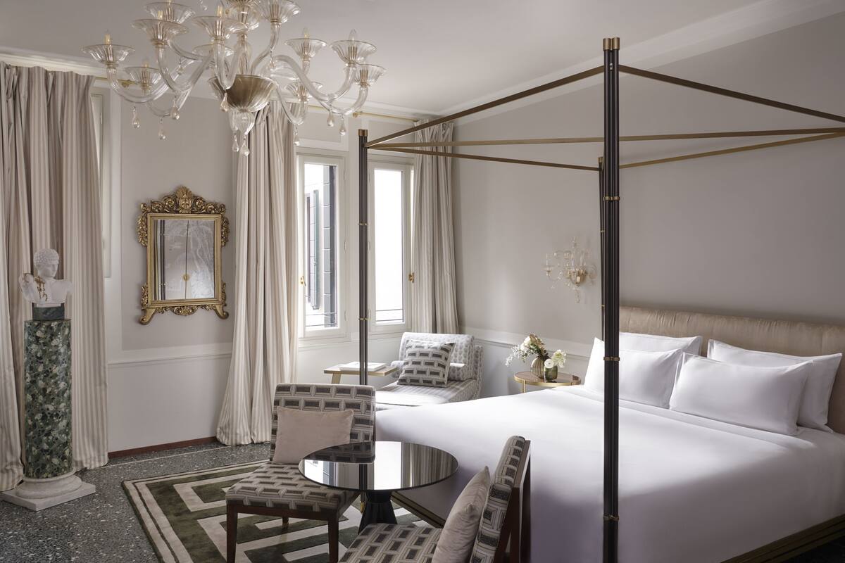A luxurious bedroom with a four-poster bed, a chandelier, and a classic decor style.