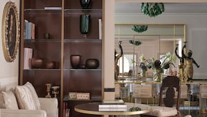A well-furnished living room with a sofa, a glass coffee table, a bookshelf, and a mirror reflecting the room. - Violino D’Oro Venezia (Venice)