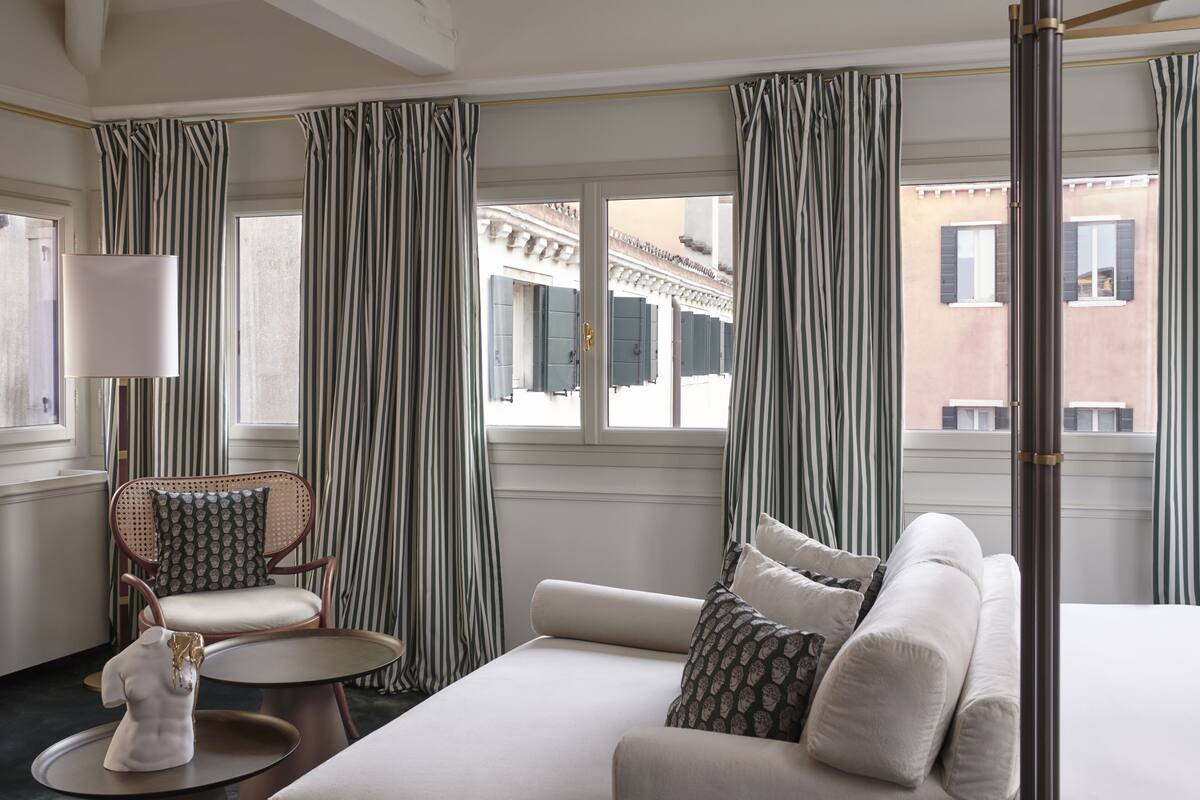 A hotel room with a bed, a chair, a table, and curtains.
