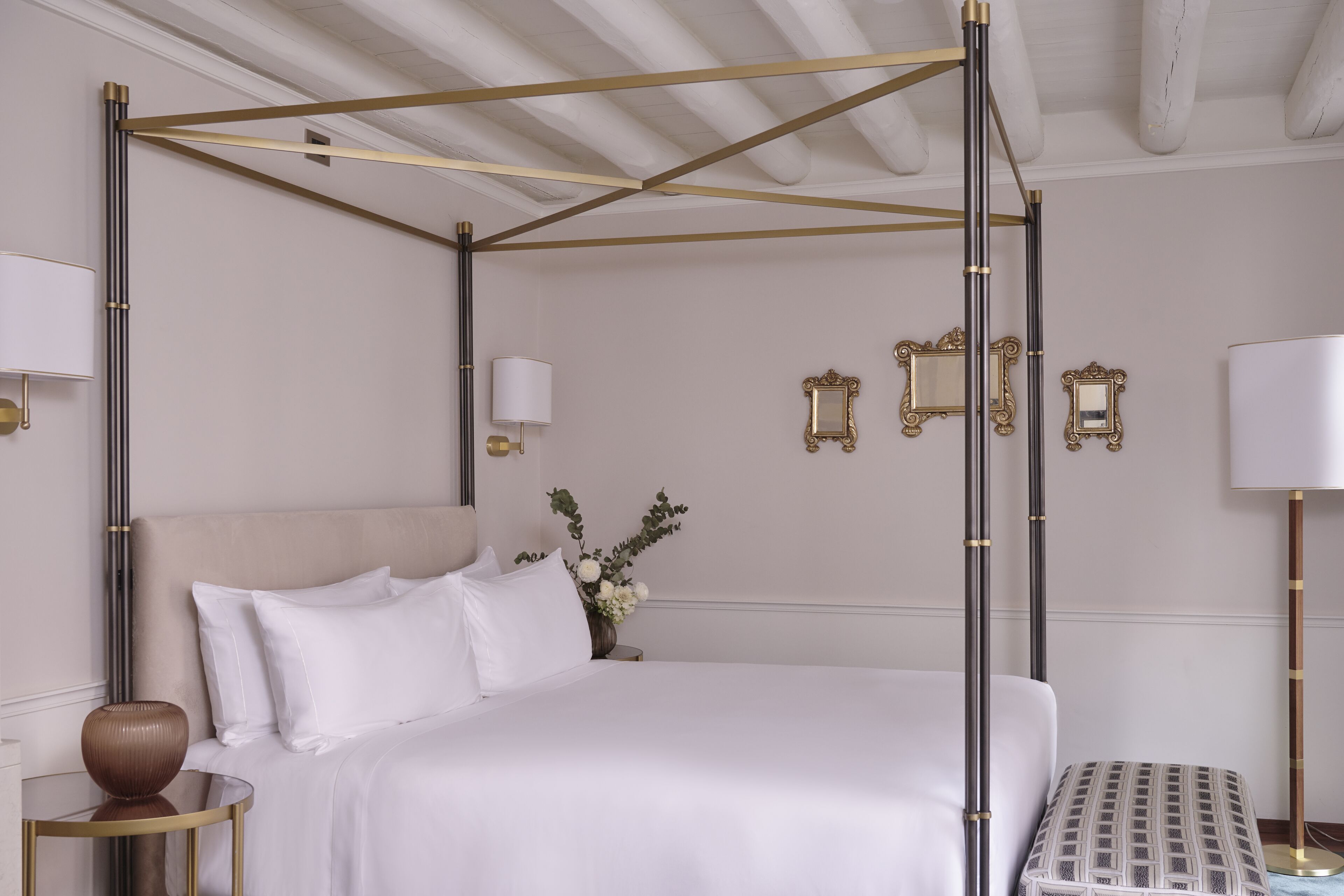 Un dormitorio ordenado con cama con dosel, mesitas de noche y lámparas de pared.