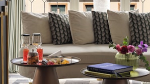 A modern living room with a sofa, two coffee tables, a decorative vase, and a view of a building through a geometric window. - Violino D’Oro Venezia (Venice)