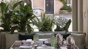 A dining area with a table set for four, overlooking a street with buildings and greenery. - Violino D’Oro Venezia (Venice)