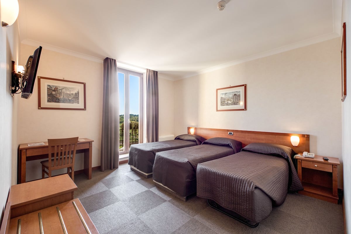 Une chambre d’hôtel avec deux lits, un bureau et une chaise.