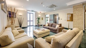Eine moderne Lobby mit beigen Sofas, einem Couchtisch und einer Wand aus Stein.
