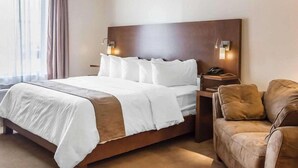 Ein Hotelzimmer mit einem großen Bett, zwei Nachttischen, einem Sofa und einem Fenster mit Vorhängen.