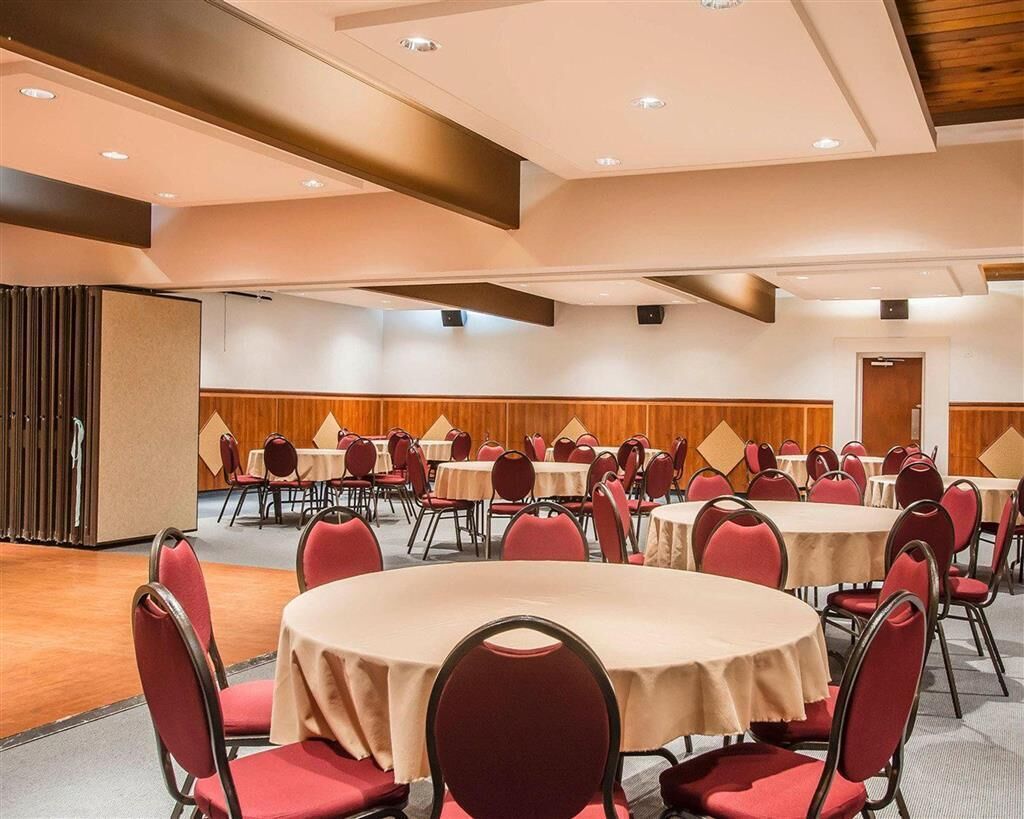 A conference room with round tables and red chairs, wooden paneling on the walls, and recessed lighting on the ceiling.