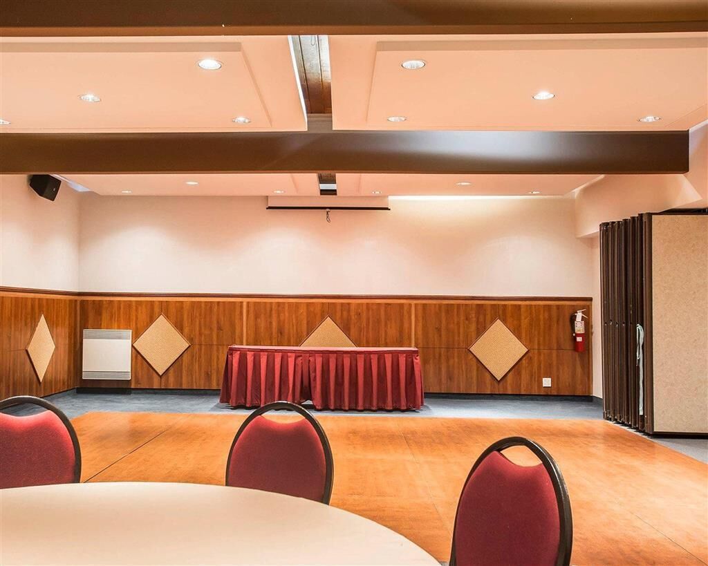 A conference room with a wooden panel wall, a red table with a matching tablecloth, and red chairs.