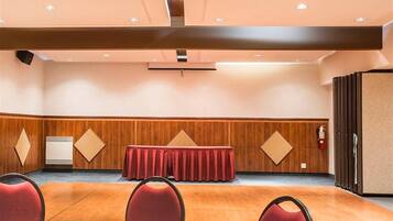 A conference room with a wooden panel wall, a red table with a matching tablecloth, and red chairs.