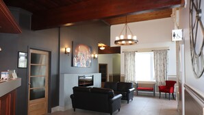 Ein großzügiges Wohnzimmer mit Kamin, schwarzen Sofas und einem roten Sessel.
