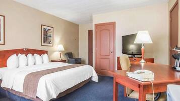 A hotel room with a bed, two bedside tables with lamps, a TV, a desk with a telephone, and a door.