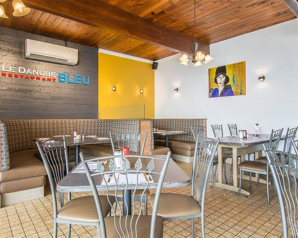A restaurant interior with booths and tables, a wooden ceiling, and a wall-mounted air conditioner.