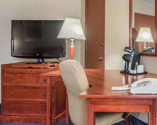A hotel room with a wooden desk, a television, a lamp, a telephone, and a coffee maker. - Hotel Danube Bleu (Forestville)