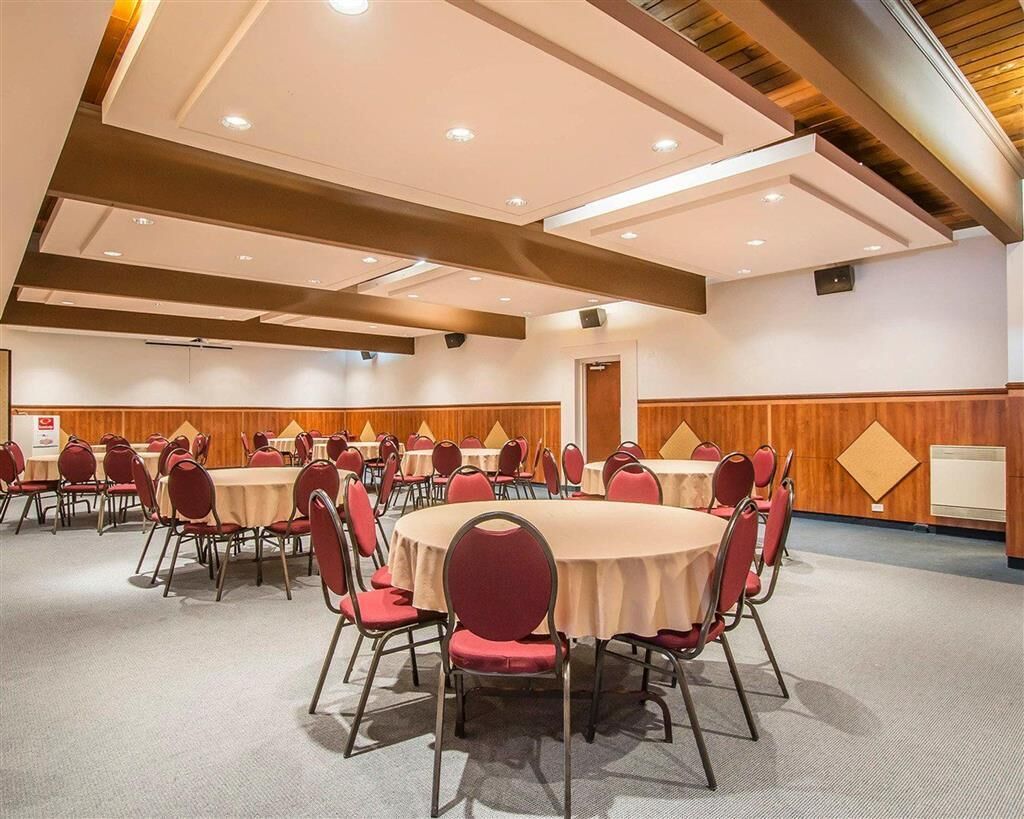 A conference room with round tables and red chairs, wooden paneling on the walls, and recessed ceiling lighting.