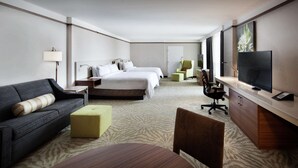 A hotel room with a bed, a sofa, a desk, a TV, and a chair.