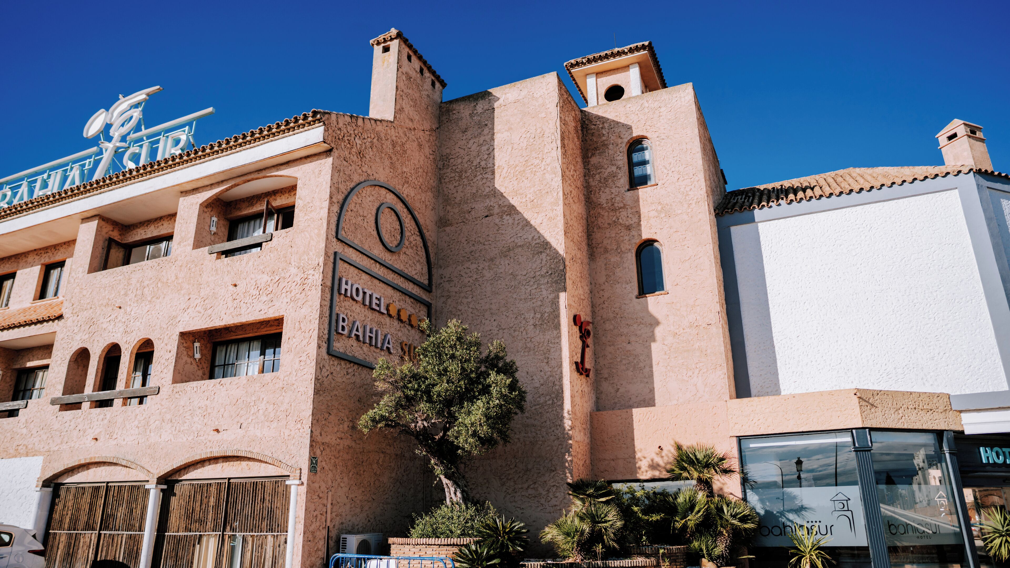 A hotel with a textured facade, arched windows, and a sign indicating it is the Bahia Hotel.