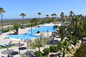 Un complexe hôtelier doté d’une grande piscine, de palmiers et offrant une vue sur la plage et l’océan.
