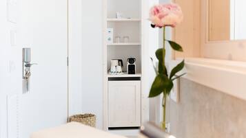 Un baño con lavamanos blanco, un espejo y una rosa en un florero.