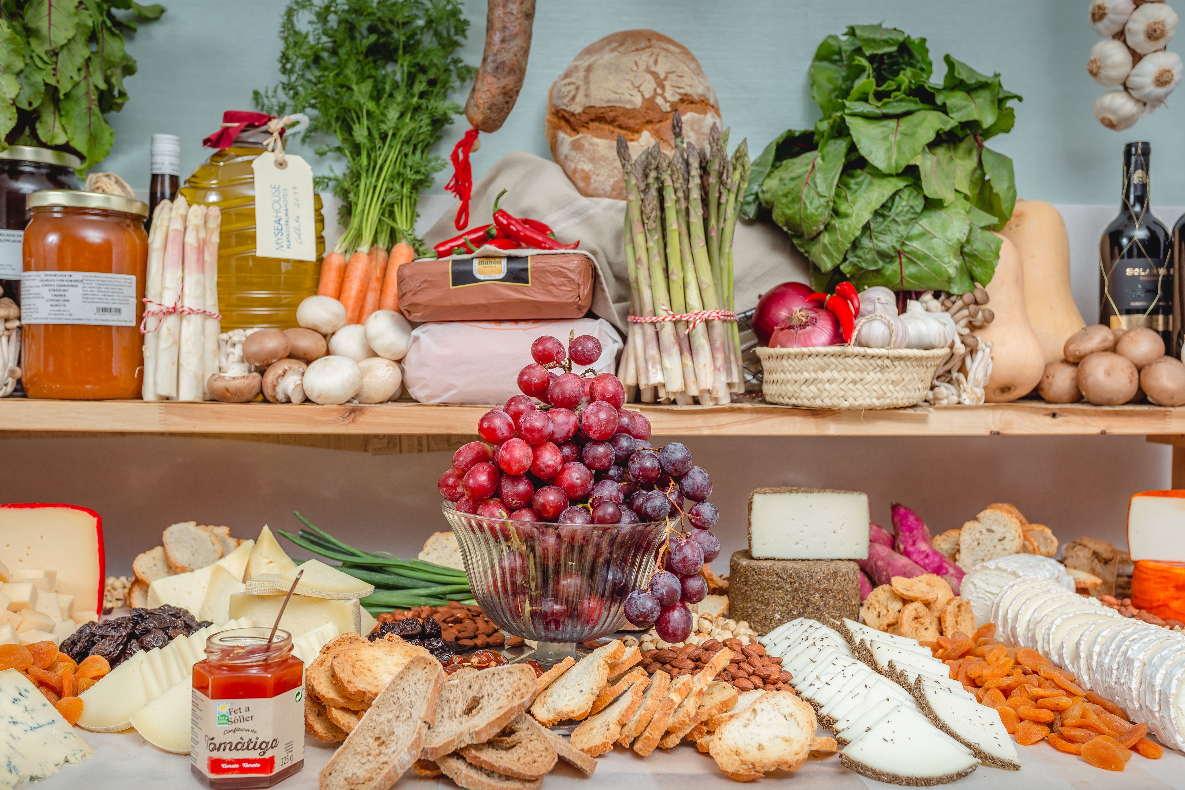 Una selección de quesos, pan y frutas sobre una mesa.