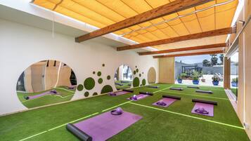 Un gimnasio con césped artificial verde, colchonetas de ejercicio moradas y vigas de madera.