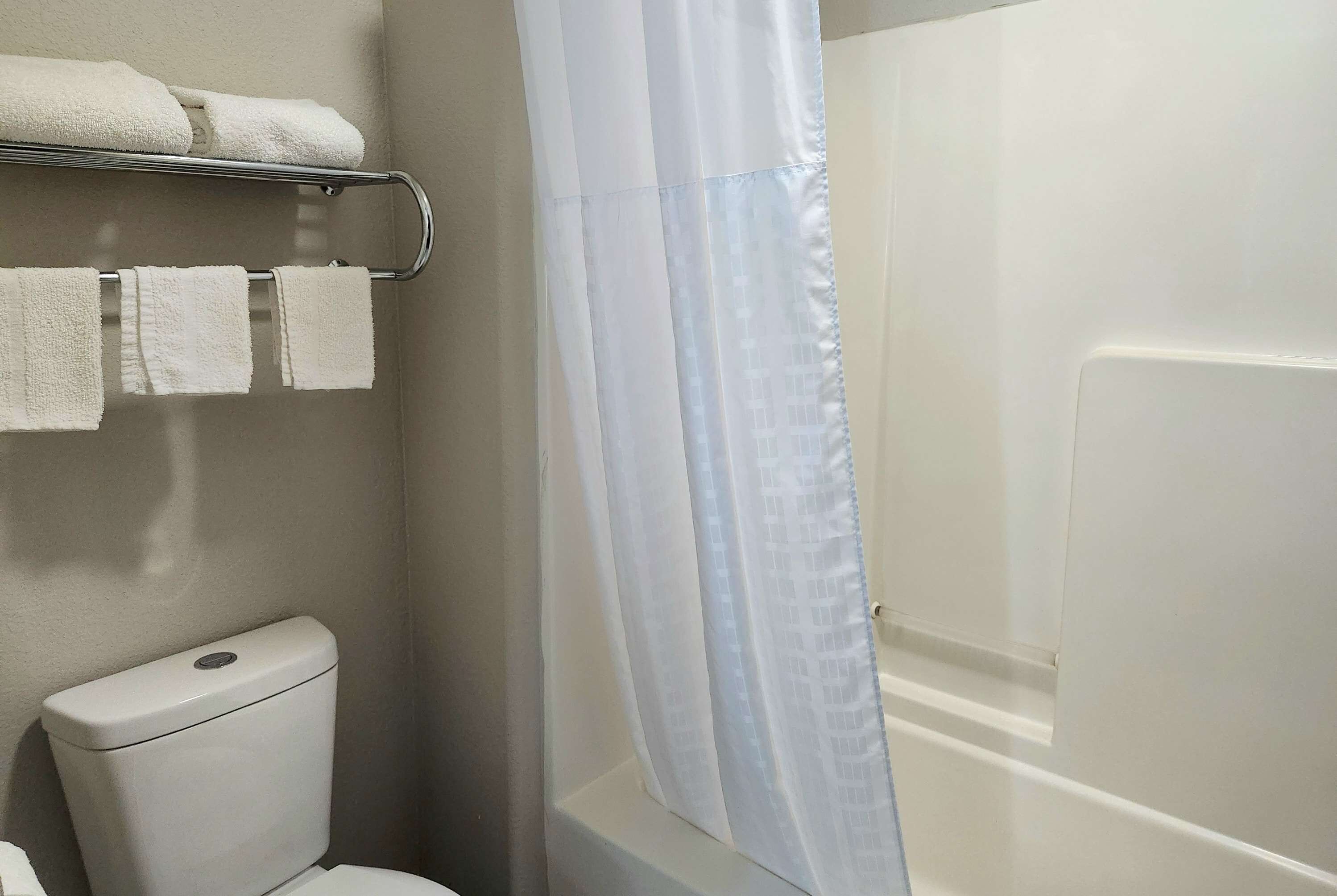 Un baño con inodoro, toallero y cortina de ducha.