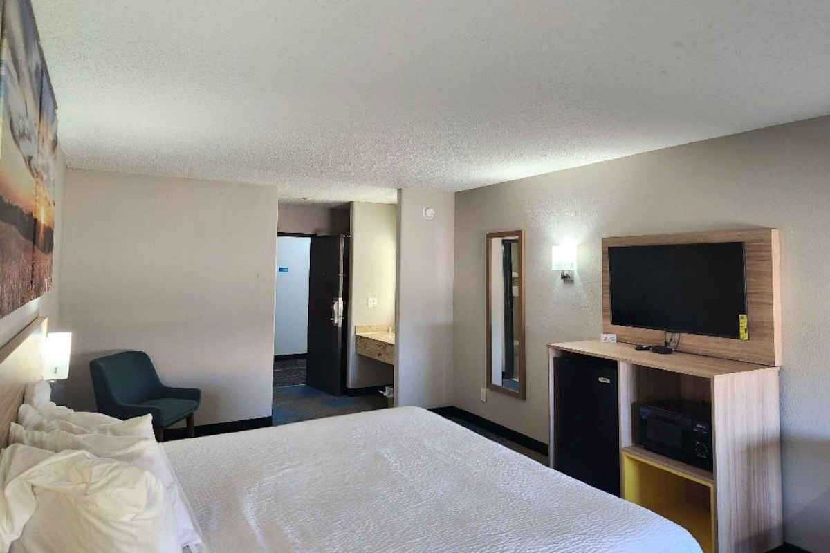 Una habitación de hotel con cama, televisión, escritorio y una silla.