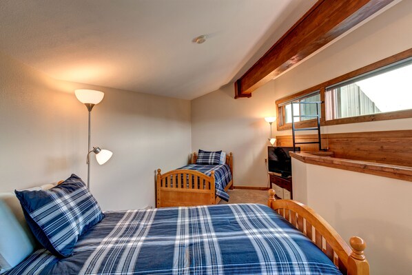 A bedroom with two beds, a wooden headboard, a desk, and a window.
