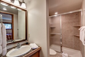 Experience a comfortable stay with a well-appointed bathroom featuring a large mirror, sink, and shower area.