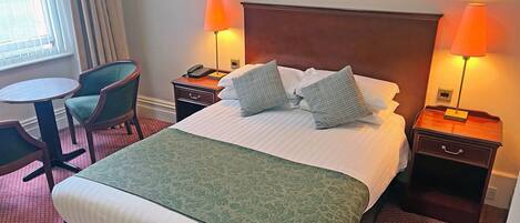 A hotel room with a bed, two nightstands, a desk, and a chair.