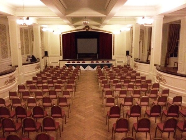 A conference room with rows of chairs facing a stage with a large screen. - Cumbria Grand Hotel (Grange-over-Sands)