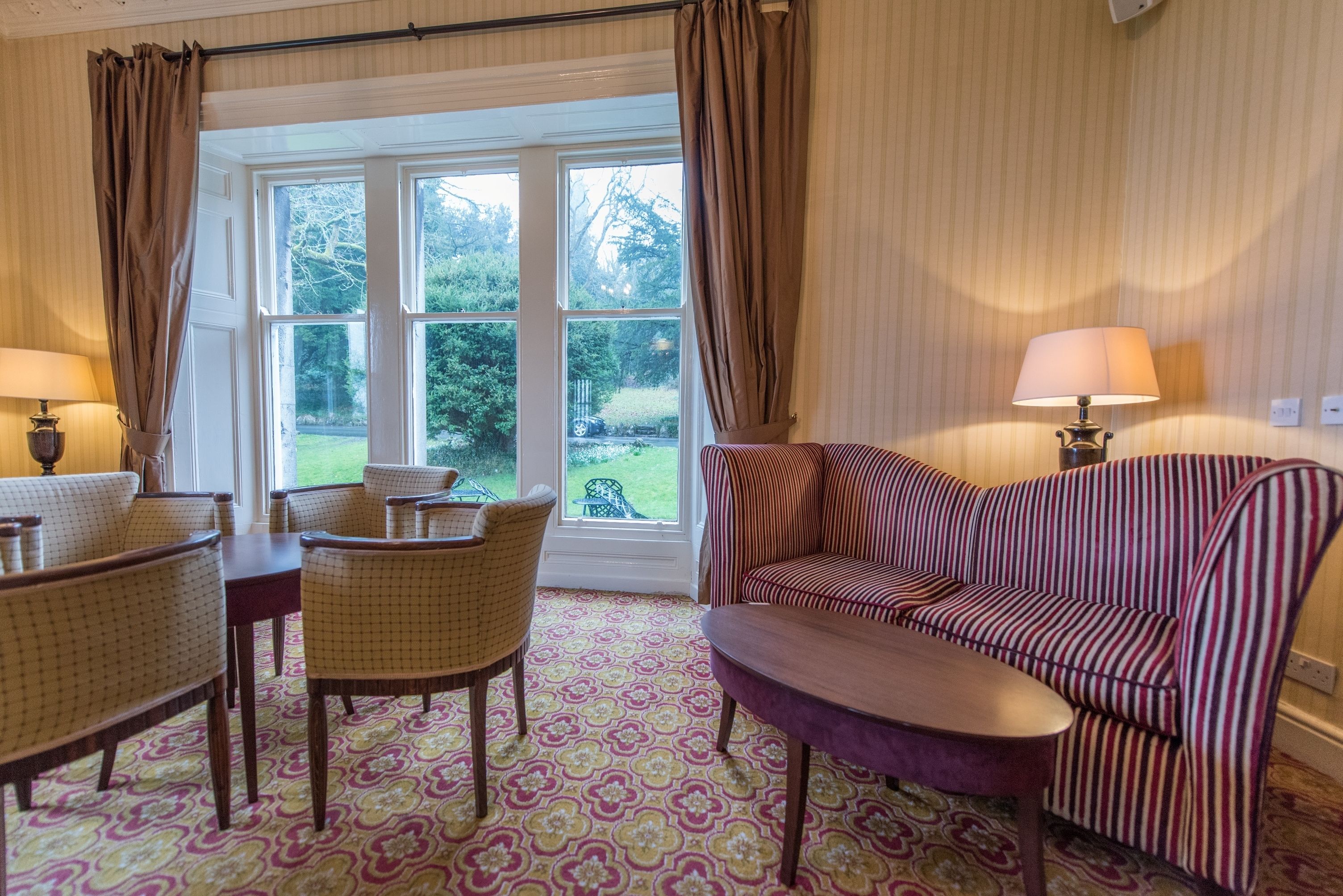 Une pièce avec un tapis à motifs, un canapé, une table à manger avec des chaises et une fenêtre avec des rideaux.