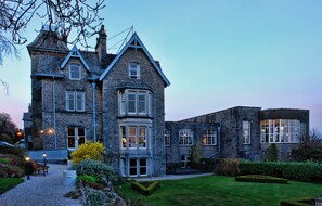 A large stone building with multiple windows and a well-maintained lawn. - Cumbria Grand Hotel (Grange-over-Sands)