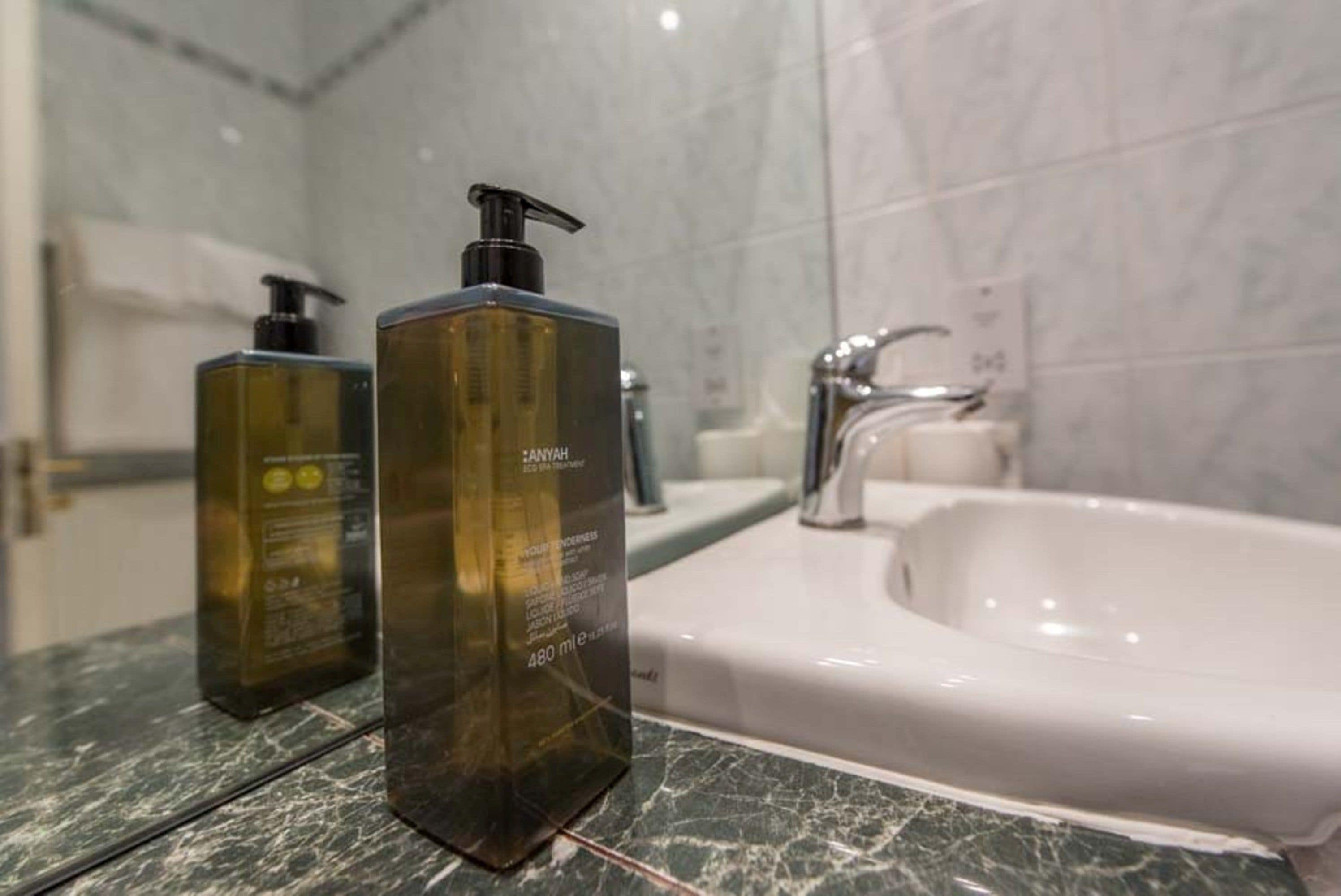 Ein Badezimmer mit Marmorplatte, zwei Seifenflaschen und einer weißen Badewanne.
