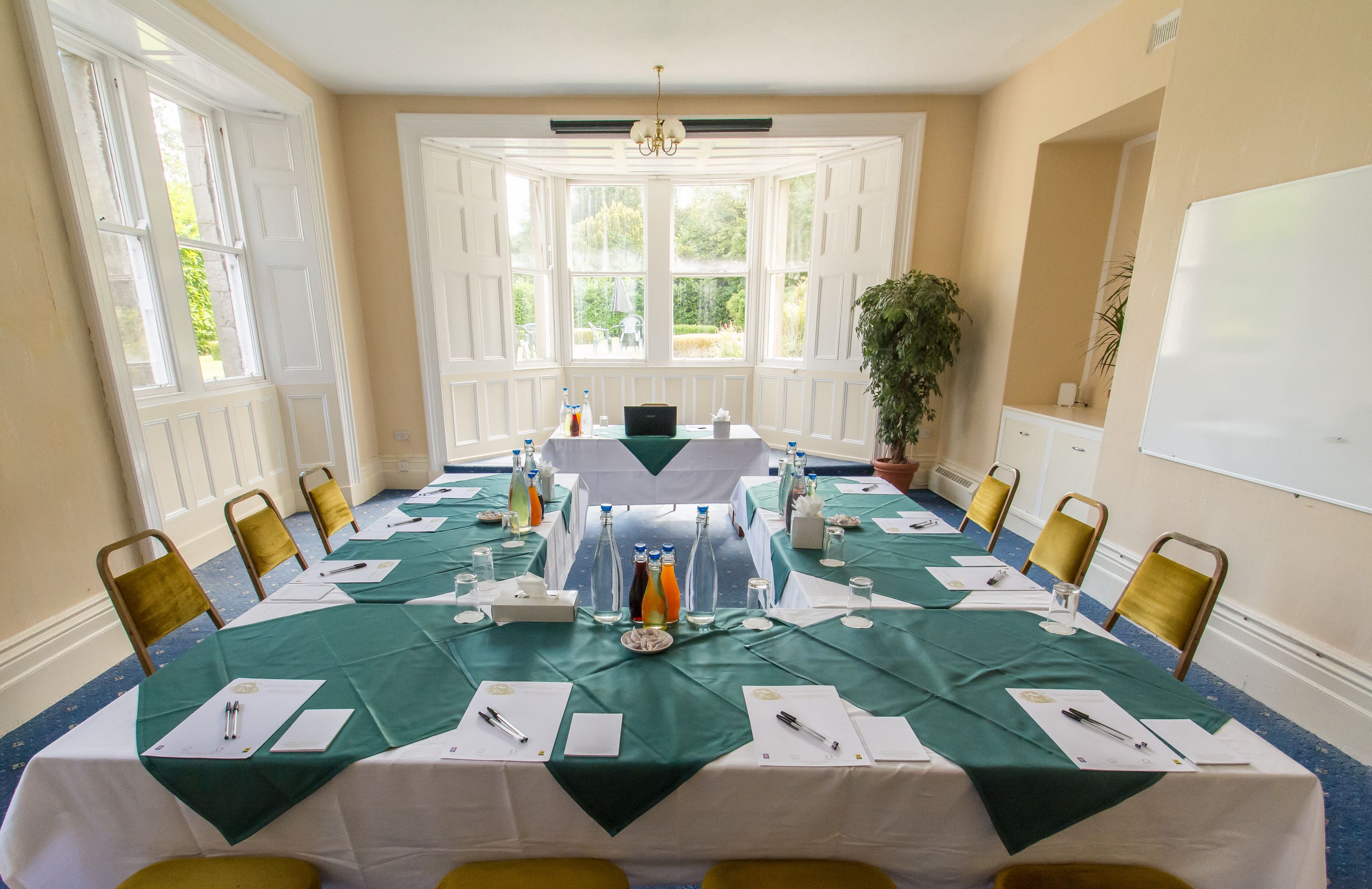 A conference room with a long table, chairs, and a whiteboard.