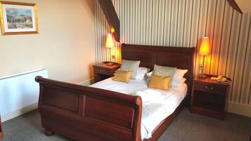 A neatly arranged hotel room with a large bed, two bedside tables, and a small round table.