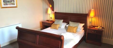 A neatly arranged hotel room with a large bed, two bedside tables, and a small round table.