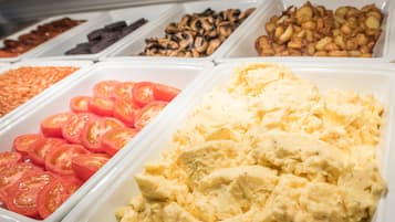 A buffet with various food items including sliced tomatoes, scrambled eggs, and different types of nuts.
