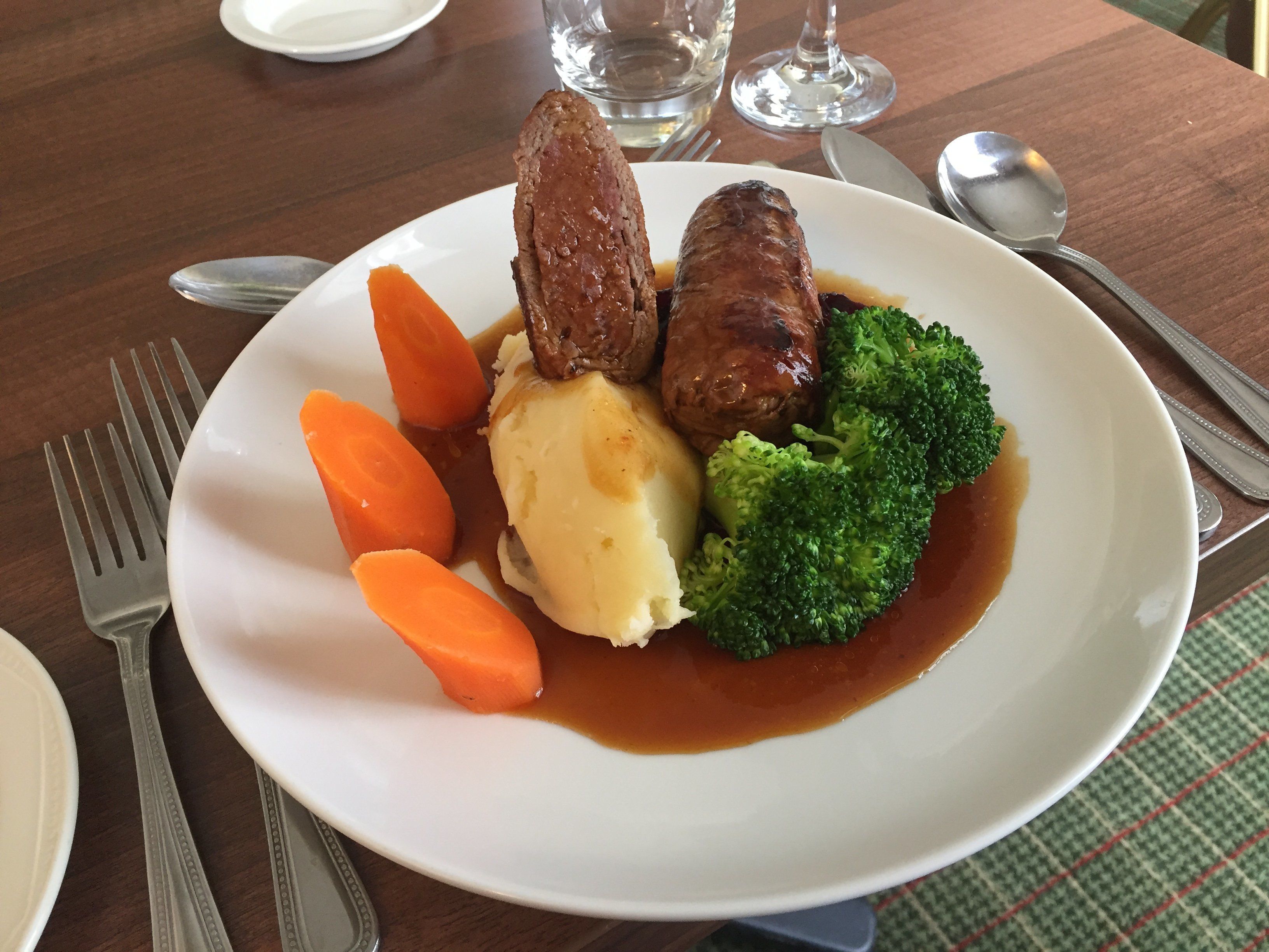 A plate of food with sausages, mashed potatoes, carrots, and broccoli.