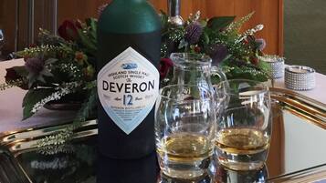 A bottle of Highland Single Malt Scotch Whisky, The Deveron 12, on a tray with two glasses of whisky.